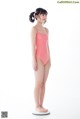 A young girl in a pink swimsuit standing on a scale.