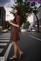 A woman in a brown dress is standing on the street.