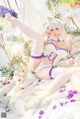 A woman in a white and purple outfit laying on a bed.