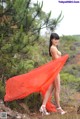 A woman in a red dress is posing for the camera.