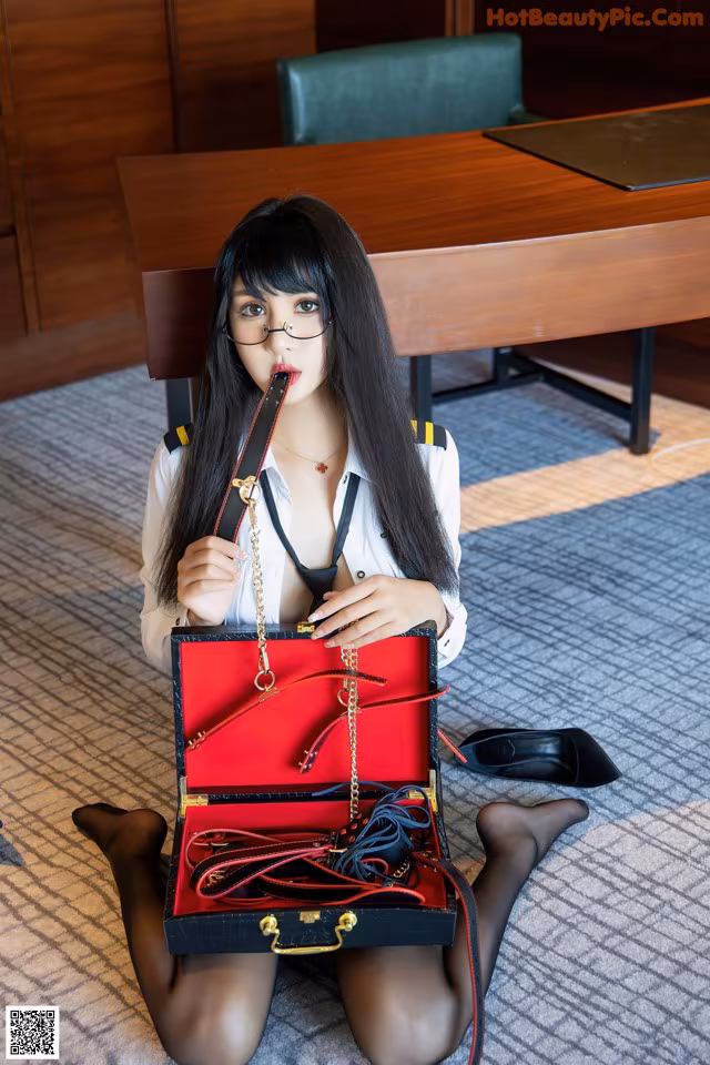 A woman sitting on the floor holding a red purse.