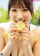 A woman holding a slice of lemon in her hand.