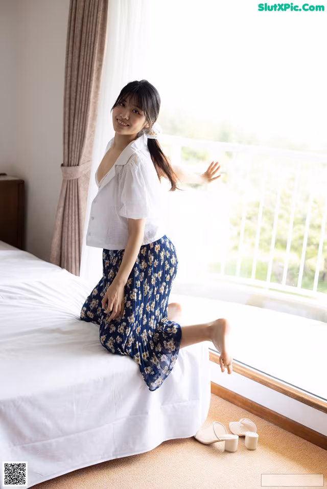 A woman sitting on a bed in a hotel room.