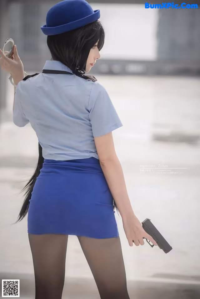 A woman in a blue uniform holding a gun.
