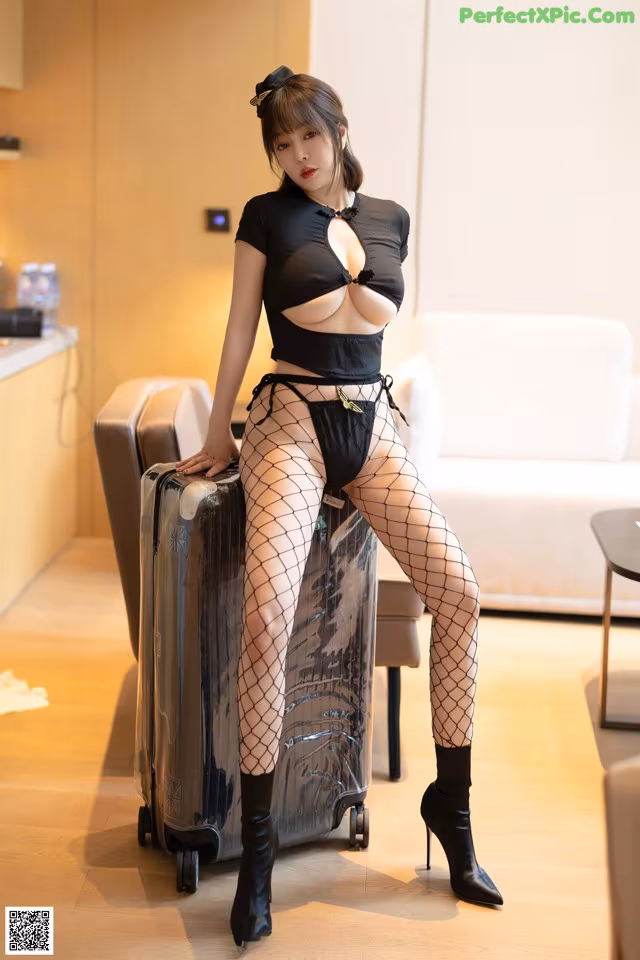 A woman in fishnet stockings sitting on top of a suitcase.