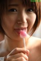 A woman holding a pink lollipop in her mouth.