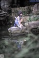 A woman sitting on a rock in the water.