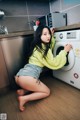 A woman sitting on the floor in front of a washing machine.