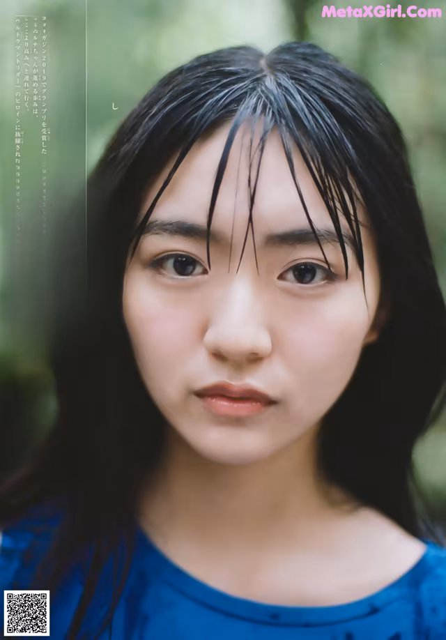 A woman with long black hair and a blue shirt.
