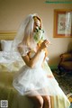 A woman in a wedding dress sitting on a bed.