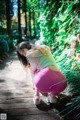 A woman in pink leggings crouching down on a wooden walkway.