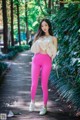 A woman in bright pink leggings standing on a wooden walkway.