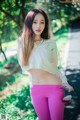 A woman in pink pants and a white hoodie posing for a picture.