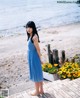 A woman in a blue dress standing on a wooden dock.