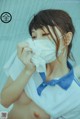 A woman wearing a face mask wiping her face with a tissue.